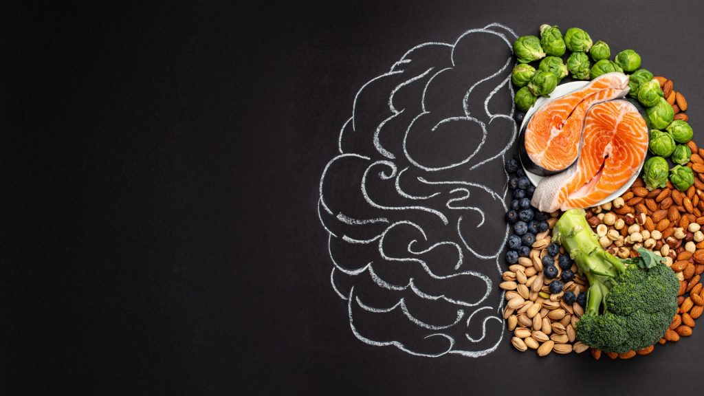 The image features a collection of food items and nuts illustrated on a blackboard. It includes various fruits and vegetables, such as carrots, showcasing a colorful and artistic representation of different food groups. The artwork highlights the importance of healthy eating in a visually engaging way.