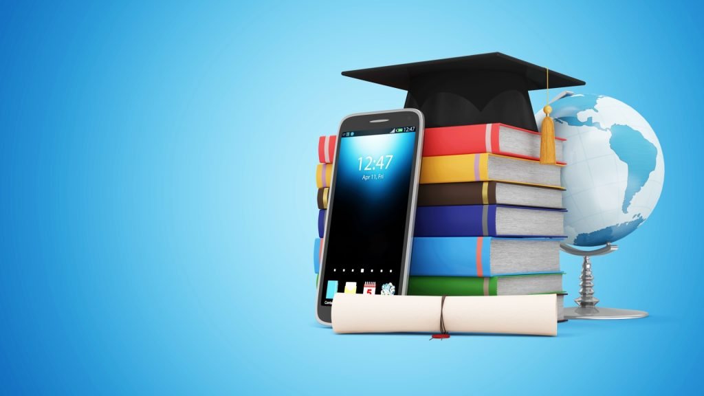 A digital rendering shows a stack of colorful books resting on a smartphone. A graduation cap sits atop the books. A rolled-up diploma/certificate is at the base of the stack, next to the phone. A globe is positioned adjacent to the book stack, positioned on a small stand. The background is a light, pale blue. The image conveys a concept of advanced learning, educational attainment, or graduation. The time displayed on the phone is 12:47 AM/PM, April 1.